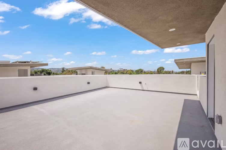 A large, empty, white room with a concrete ceiling and a view of the sky.