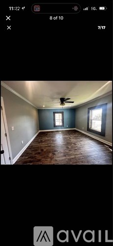 A room with a ceiling fan and two windows.