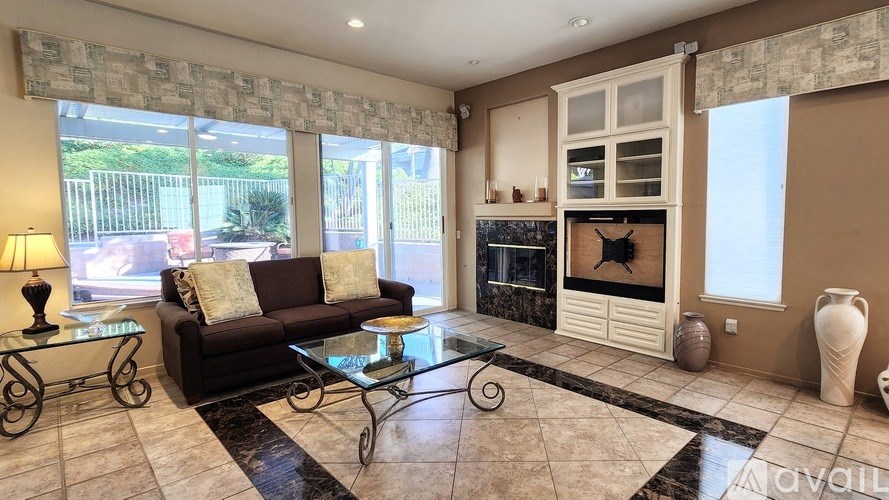 A living room with a brown couch, glass coffee table, and a fireplace.