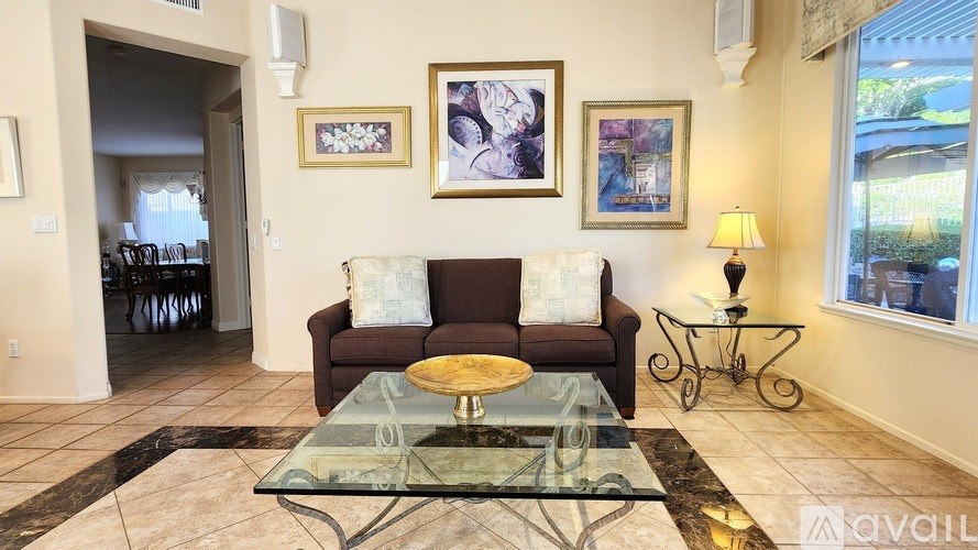A living room with a brown couch, a glass coffee table, and a lamp.