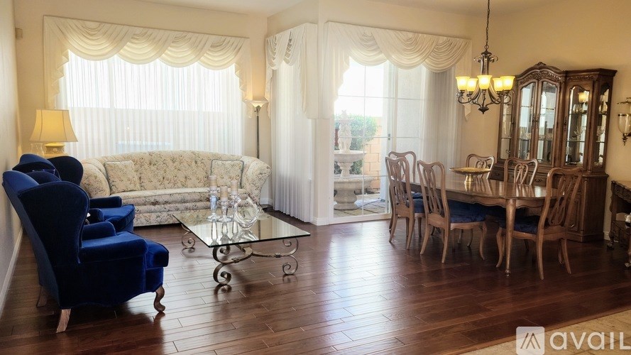 A living room with a blue chair and a glass table.