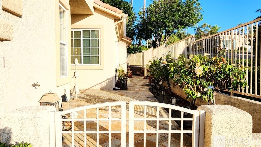A white gate leads to a patio with a table and chairs.