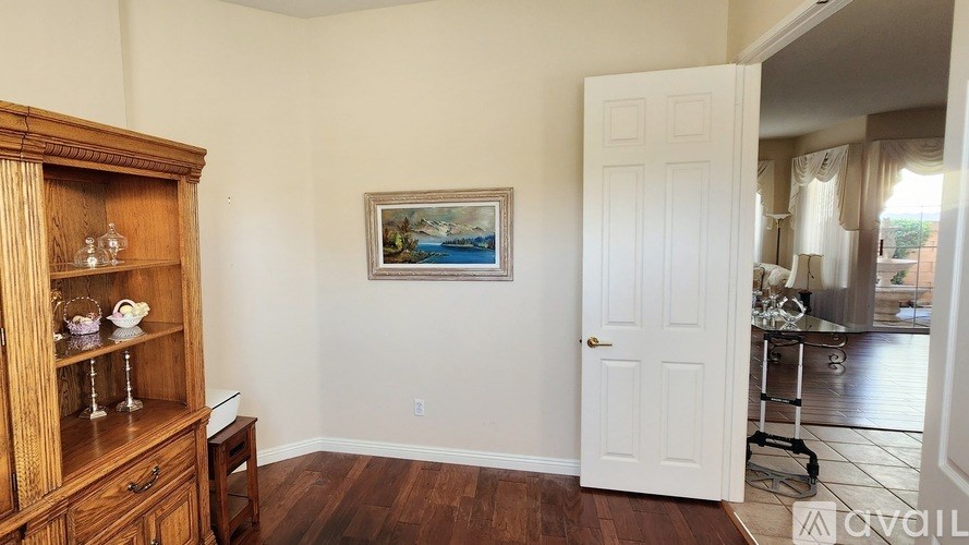 A room with a wooden cabinet and a painting on the wall.