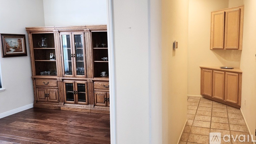 A room with a wooden floor and a wooden cabinet with glass doors.