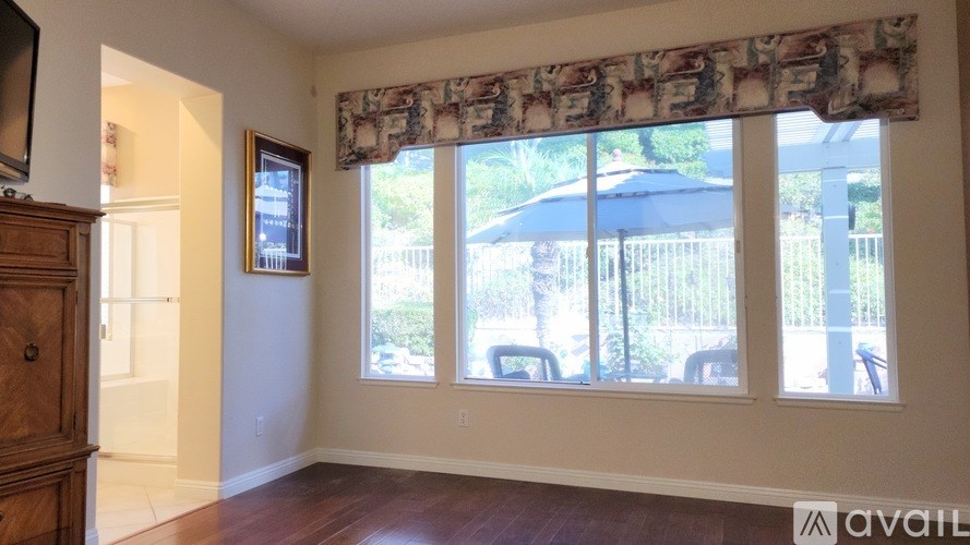 A room with a large window and a wooden cabinet.