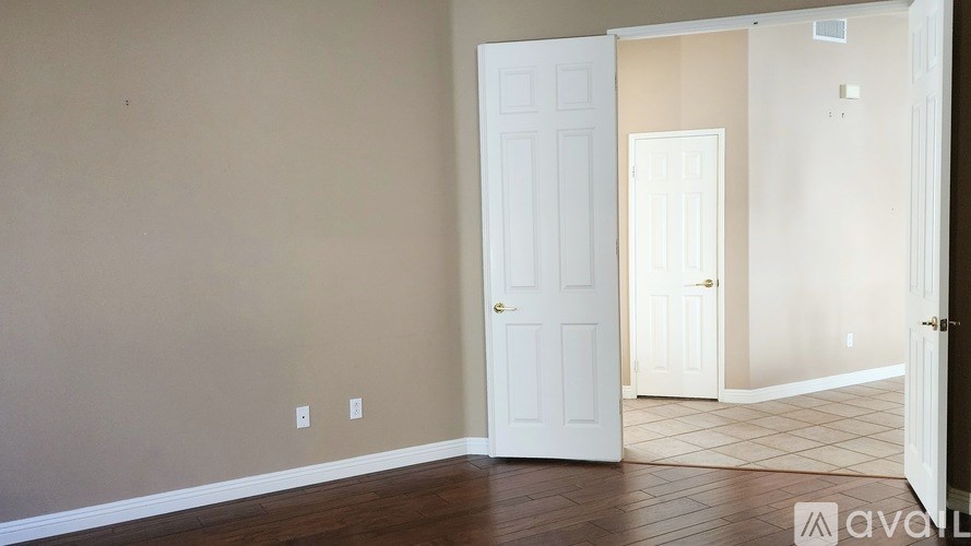 A room with a white door and a wooden floor.