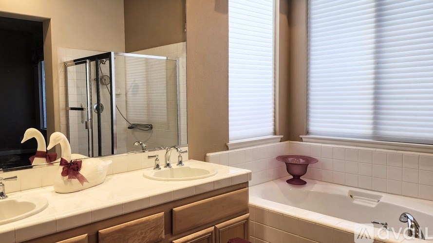 A white sink with a red bowl on top of it.