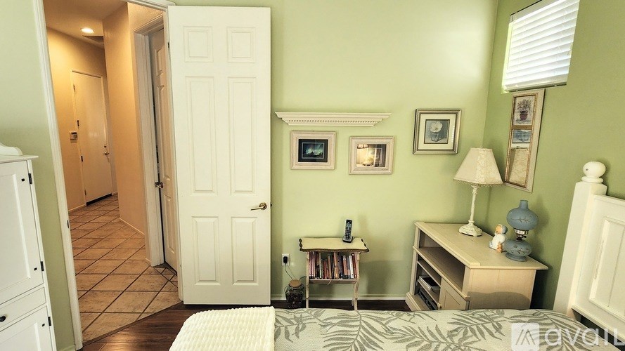 A bedroom with a bed, nightstand, and a doorway leading to another room.