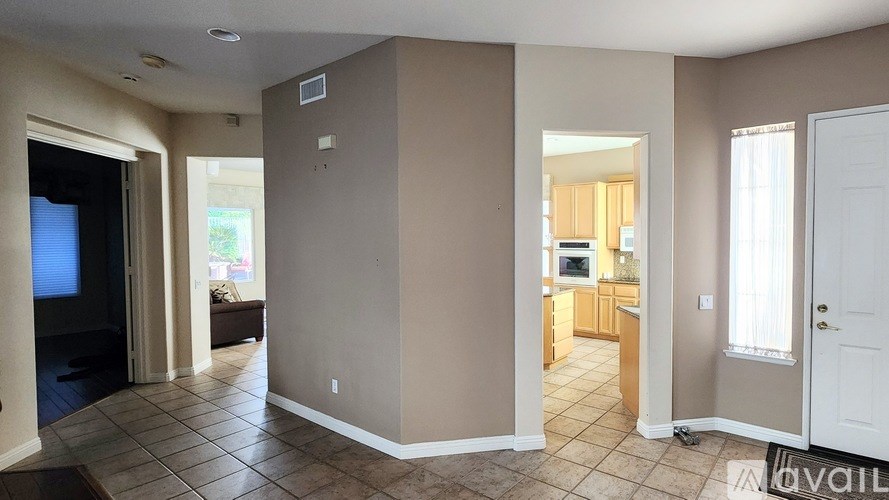 A living room with a television and a kitchen area in the background.