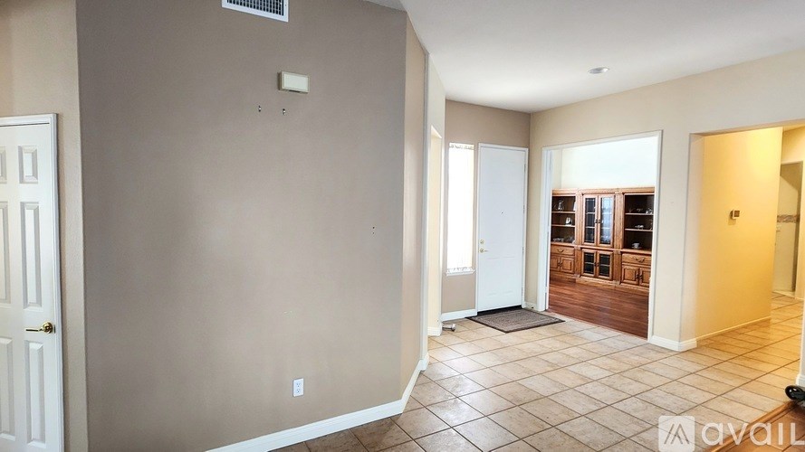 A room with beige walls and a tiled floor with a mat in the middle.