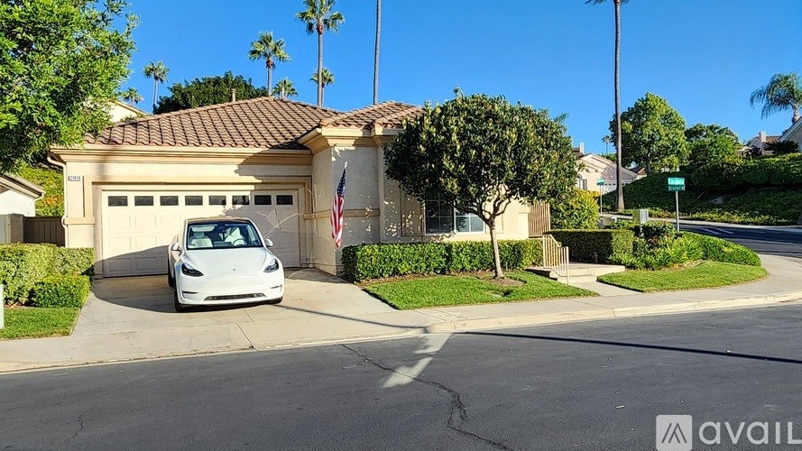 A white Tesla car is parked in front of a house.