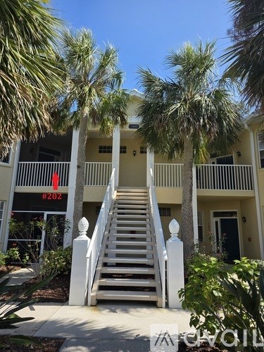 A white staircase leads to a balcony with a view of a building with the number 202 on it.
