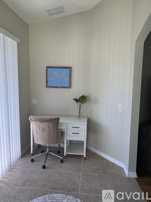 A room with a desk and chair and a painting on the wall.