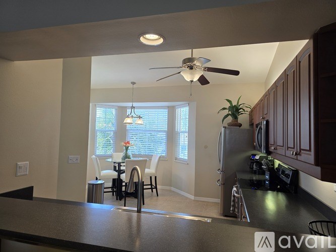 A kitchen with a black counter top and a ceiling fan.