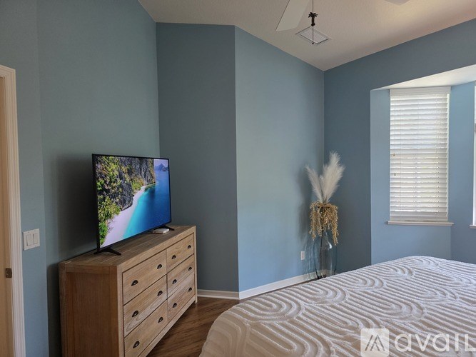 A television is on a wooden stand in a bedroom.