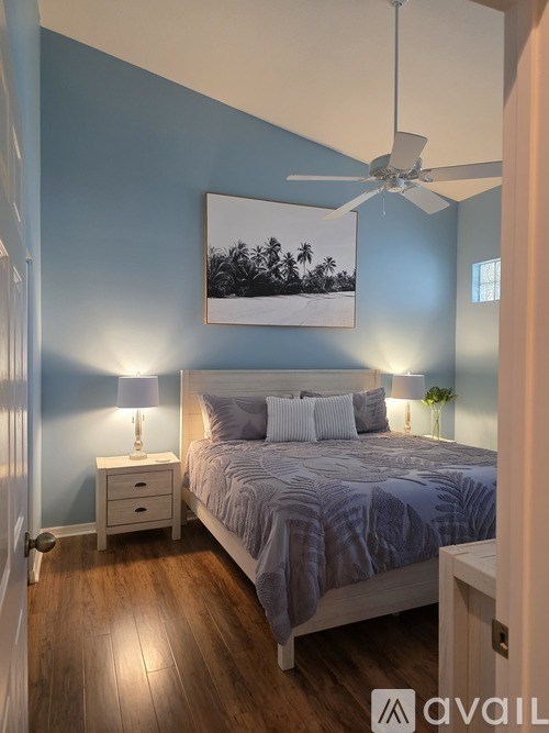 A bedroom with a bed, nightstands, and a ceiling fan.