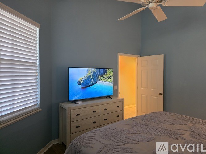 A bedroom with a bed, dresser, and television.