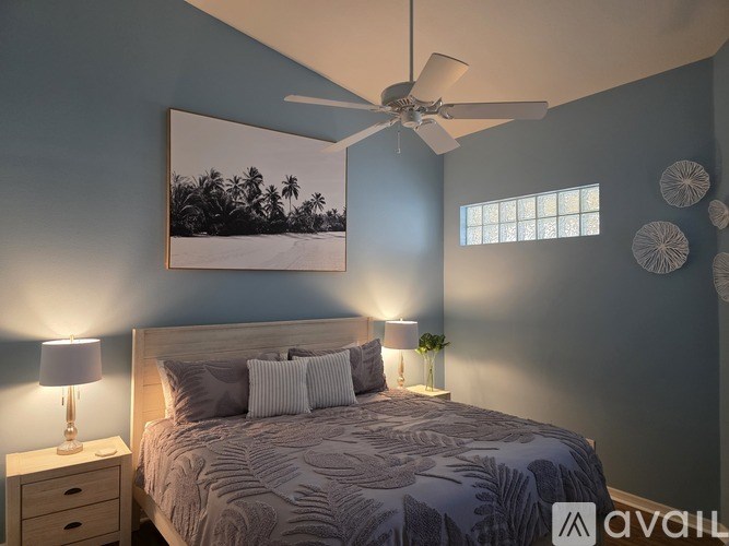 A bedroom with a bed, a ceiling fan, and a picture on the wall.