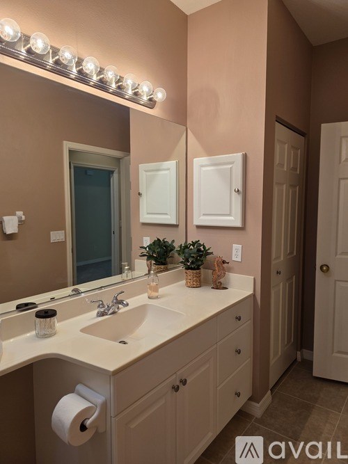 A bathroom with a sink, mirror, and lights above it.