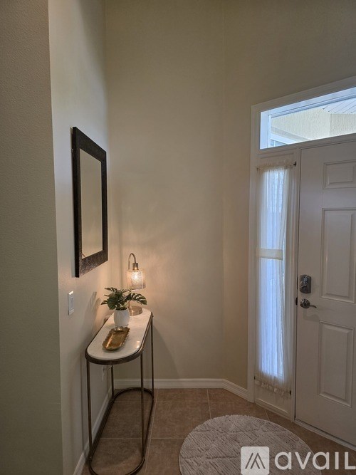 A small table with a plant and a picture frame on the wall.