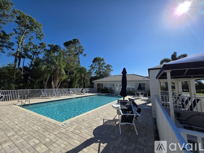 A pool area with chairs and a house in the background.
