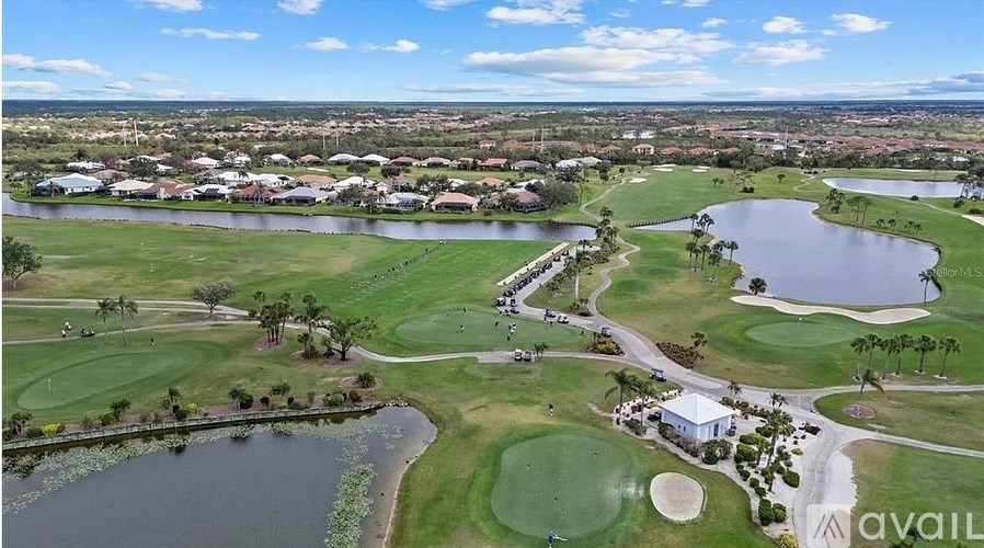 A golf course with a lake and a clubhouse.