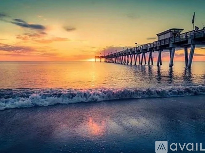 A pier extends into the water at sunset.