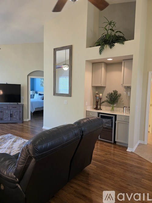 A living room with a black leather couch and a television.