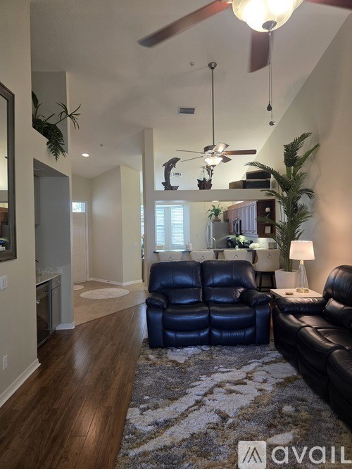 A living room with a black leather couch and a rug.