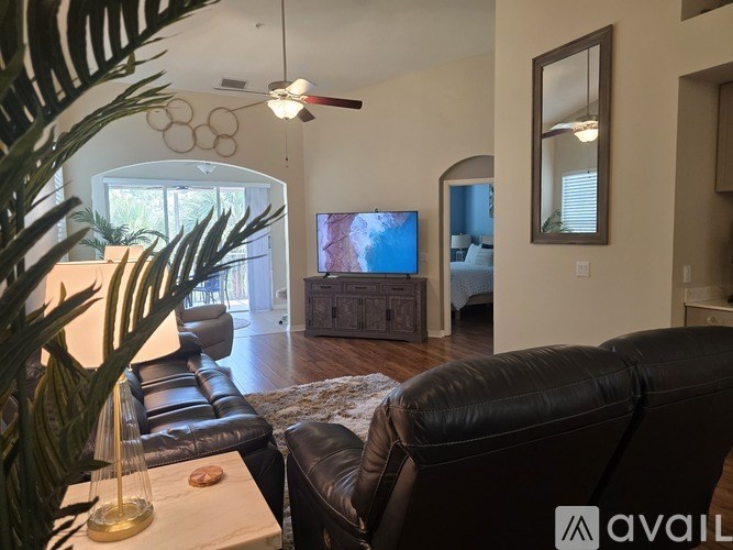 A living room with a black leather couch and a flat screen TV.