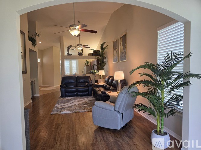 A living room with a grey couch and a fan.