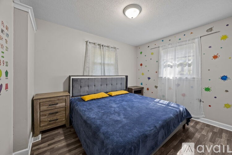 A bedroom with a blue bedspread and a wooden nightstand.
