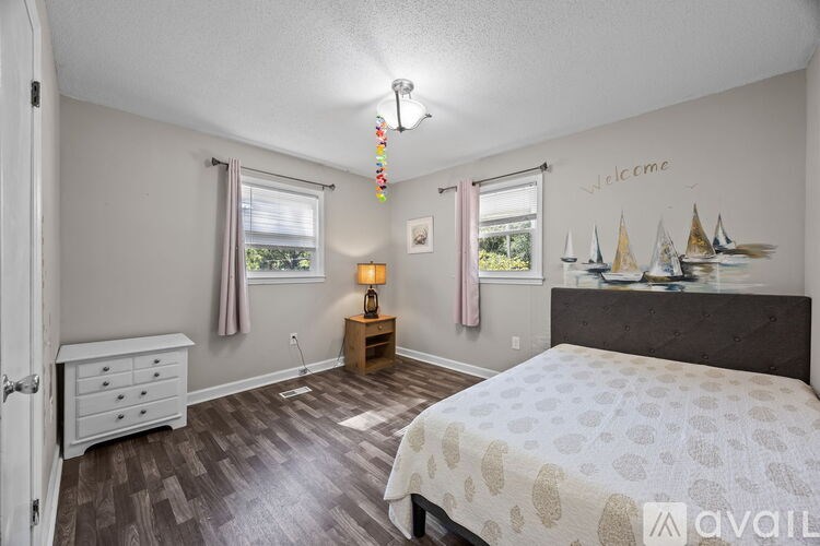 A bedroom with a bed, dresser, and window.