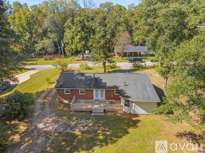 A house with a red brick exterior is surrounded by greenery.