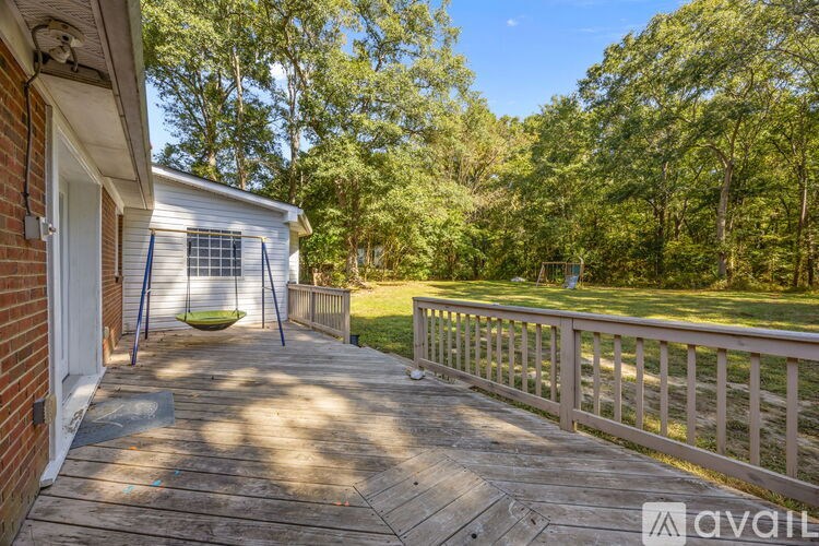A wooden deck with a swing set and a house in the background.