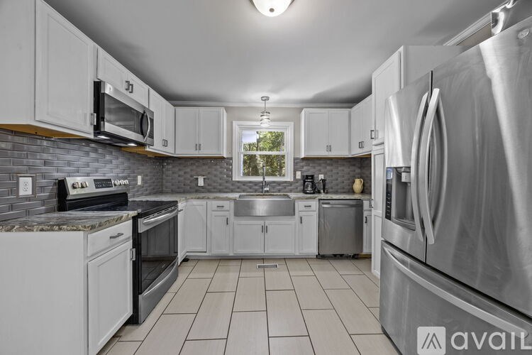 A kitchen with white cabinets and stainless steel appliances is available for rent.