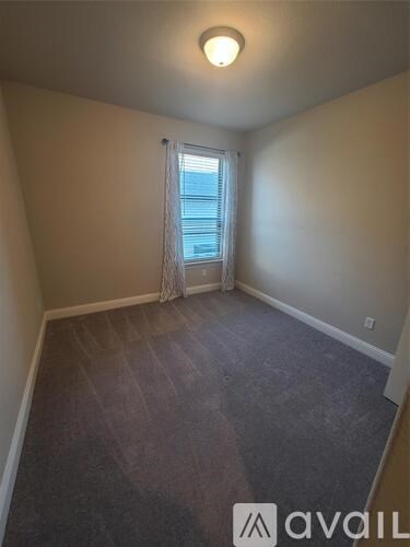 A room with a window and a carpeted floor.