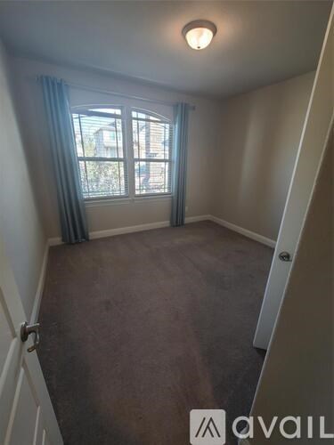 A room with a carpeted floor and a window with curtains.