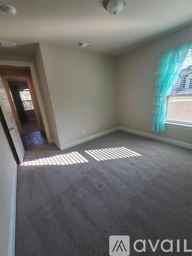 A room with a carpeted floor and a window with blinds.