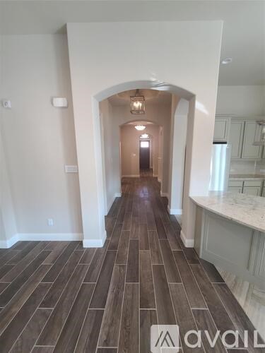 A hallway with wood flooring and white walls.