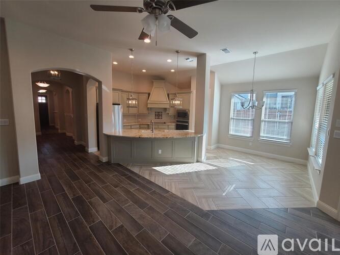 A spacious kitchen and living room with wood flooring and a ceiling fan.