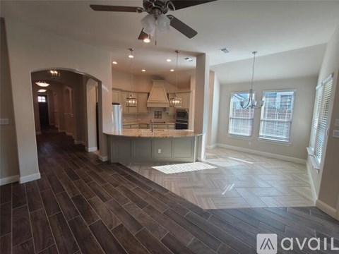A spacious kitchen and living room with wood flooring and a ceiling fan.