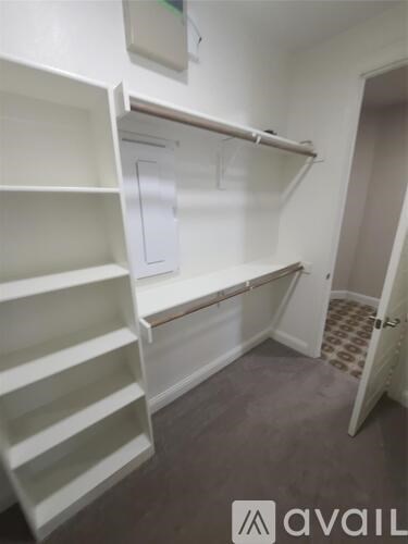 A white closet with shelves and a door.