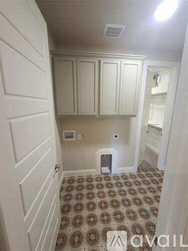 A room with a tiled floor and white cupboards.
