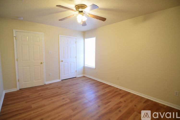 A room with a ceiling fan and wooden flooring.