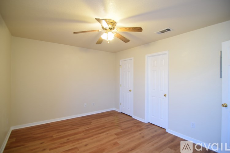 A room with a ceiling fan and wooden flooring.