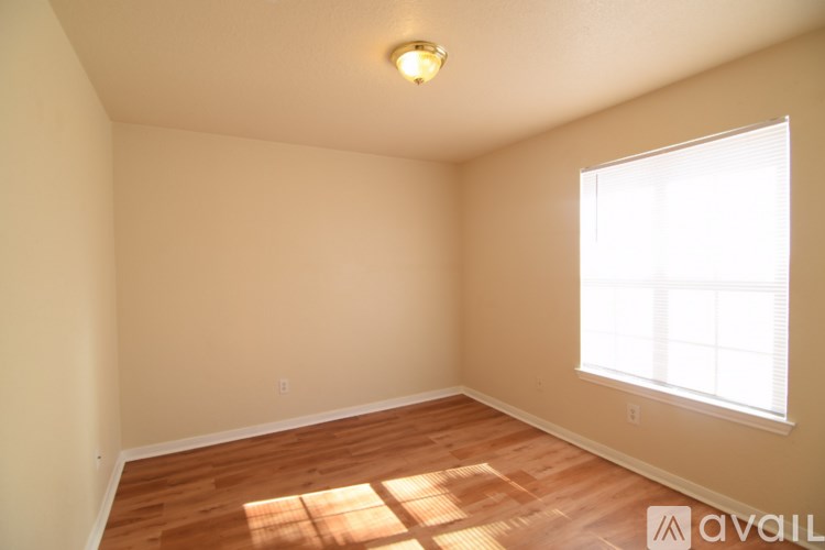 A room with wooden floors and a window letting in sunlight.