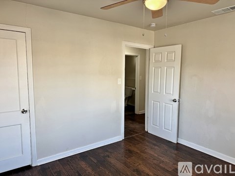 A room with a white door and a ceiling fan.