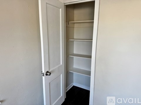 A white door is open to a white shelving unit.
