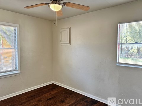 A room with a ceiling fan and two windows.